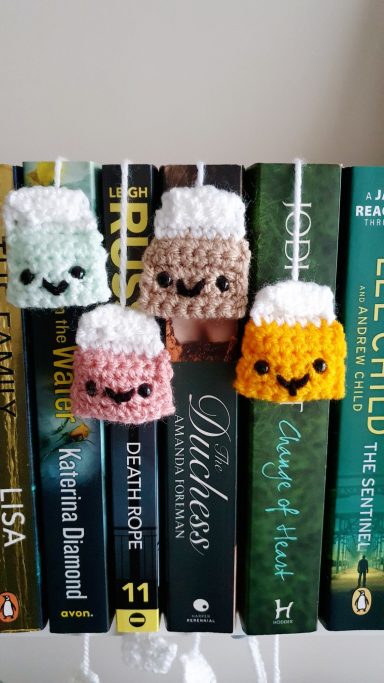 Bookmarks crocheted to look like tea bags, they are hanging out of the spine of a book