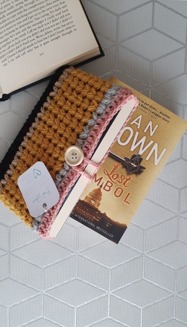 A book sleeve with 1 black stripe, 1 light brown stripe, a block of mustard yellow, then a stripe of grey and pink to look like a pencil