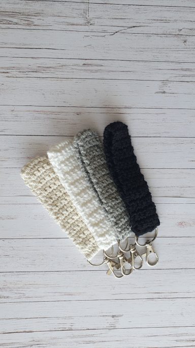 A wristlet (like a band) on a keyring in the colours white, grey, cream and black